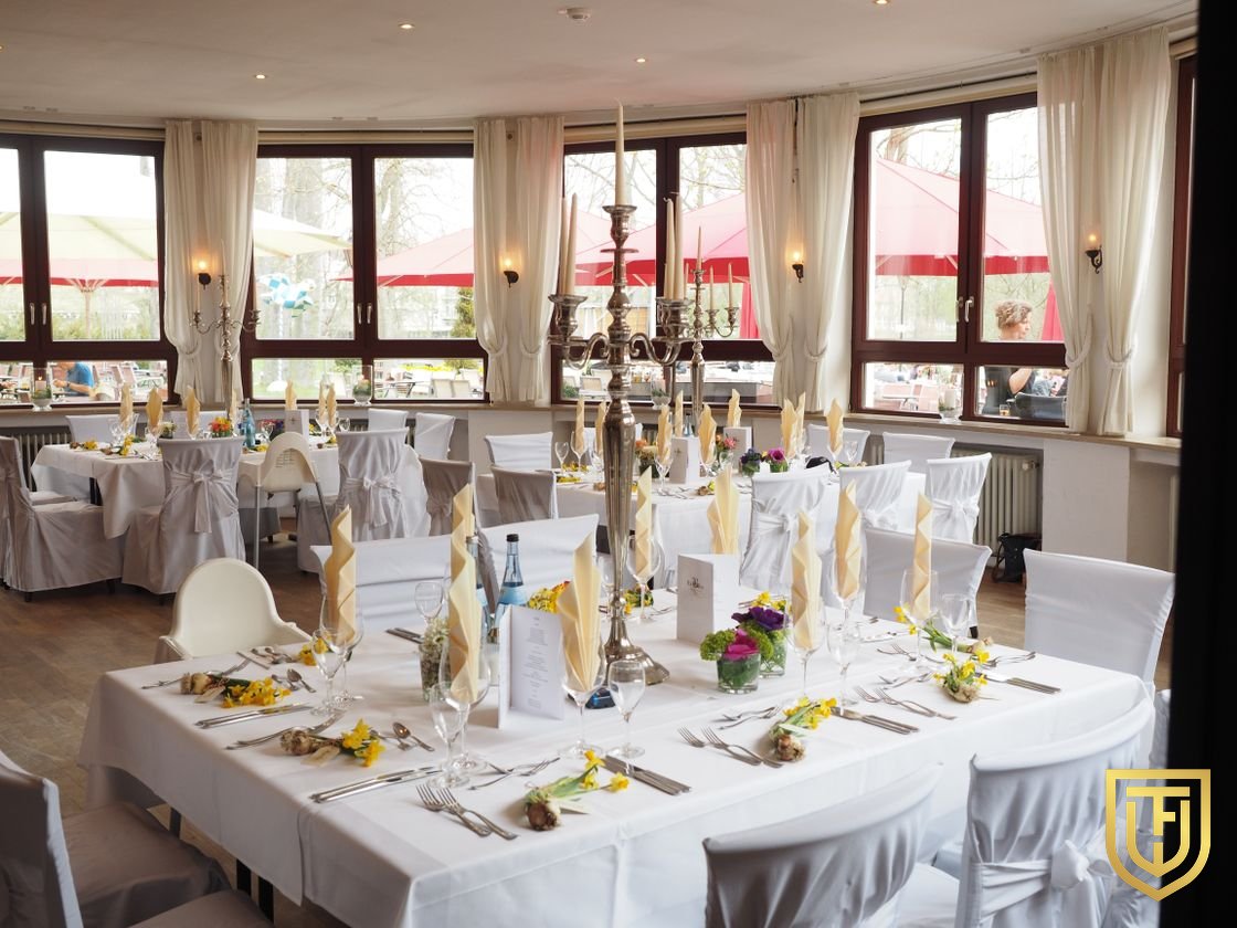 Banquet room set with white linen, candelabra, and folded napkins before service